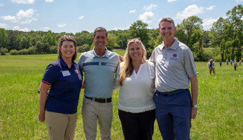Four people standing in a field posing for a photo