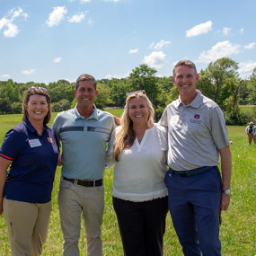 Four people standing in a field posing for a photo