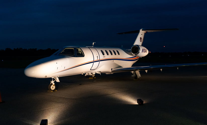 corporate jet at night on a runway with a light shining on the jet