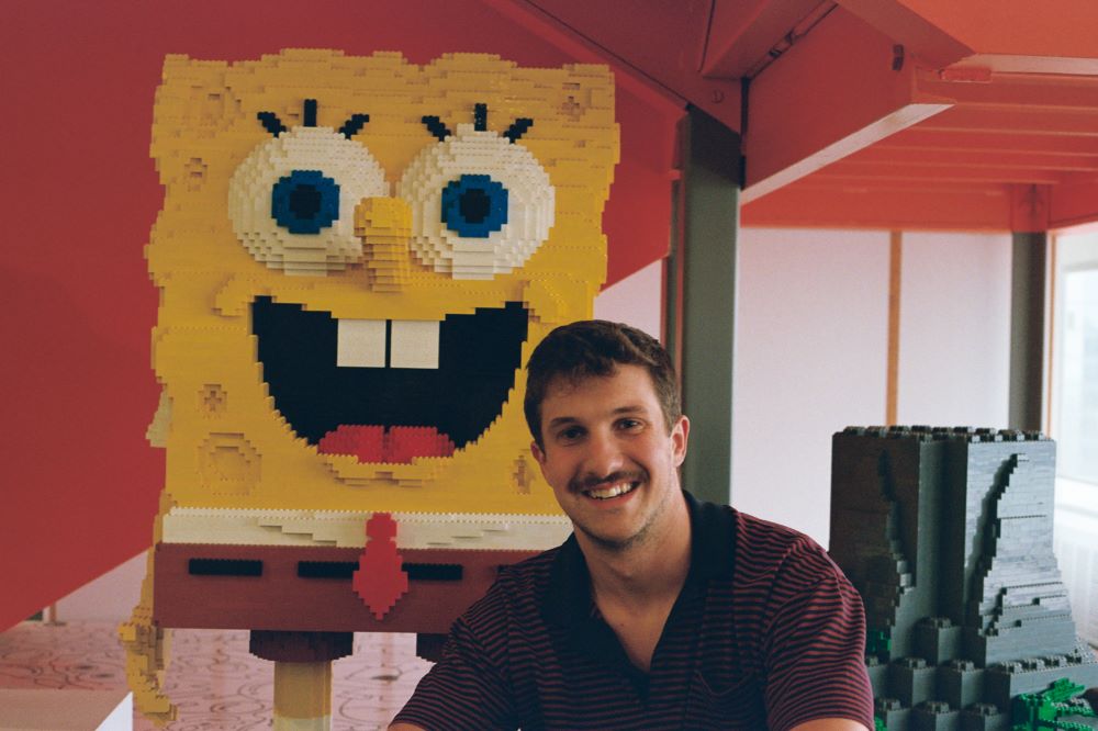 Caleb Eason sitting beside a statue of SpongeBob