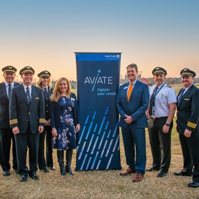 College of Liberal Arts Interim Dean Ana Franco-Watkins stands with United pilots in front of Aviate Captain your Career sign
