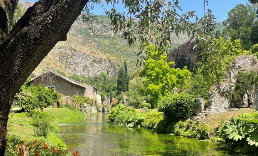 Italian countryside house with small river and mountains in background