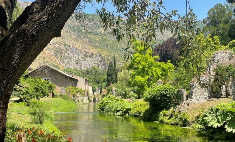 Italian countryside house with small river and mountains in background