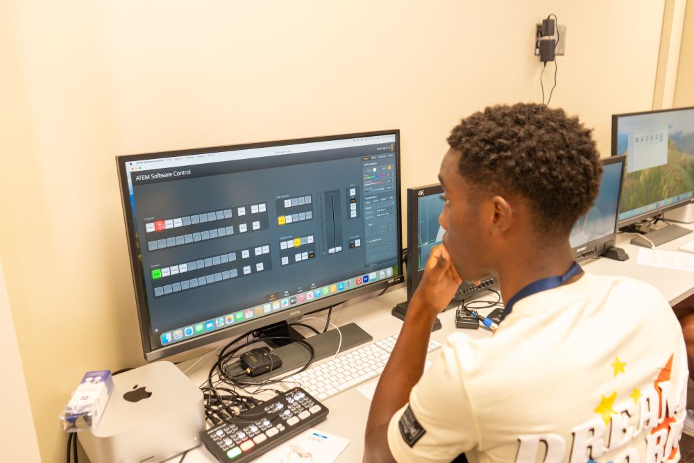 Student sitting at a computer editing a video