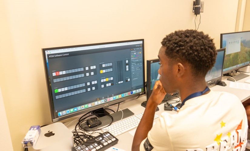 Student sitting at a computer editing a video