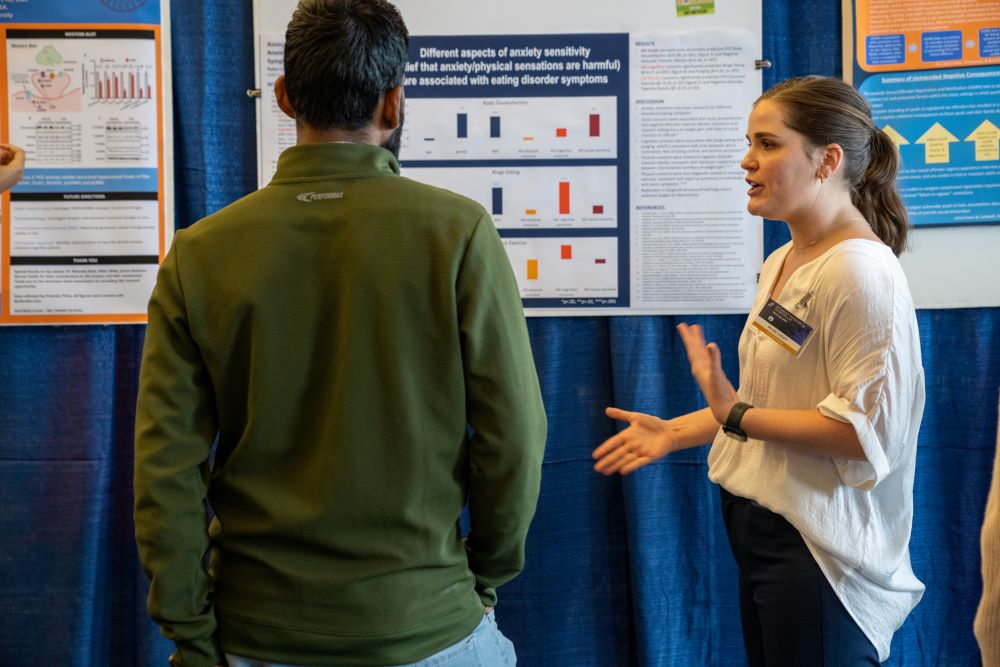 Rylee Lusich explains her research to a guest at the symposium