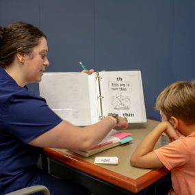 A clinician helping a child read from a practice book