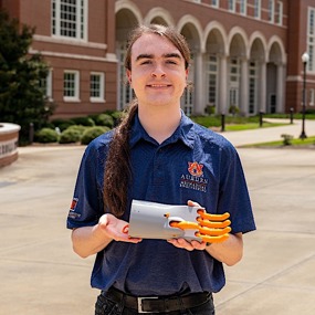 Peden Jones holding a 3-D printed recreation of a 500-year-old mechanical hand