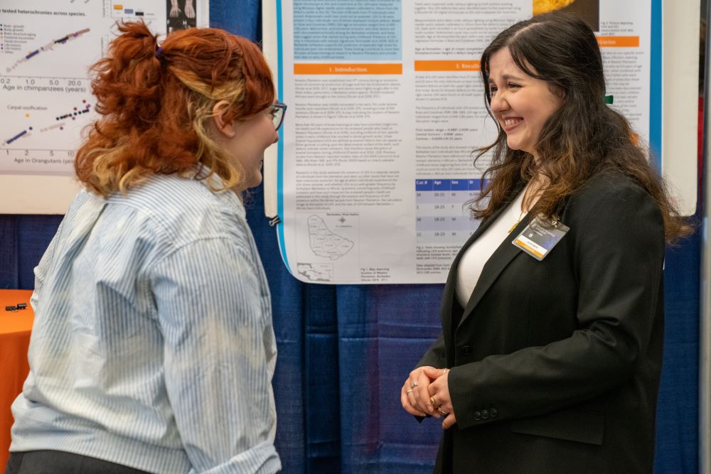 Toni Lee and Katie Smith talk to each other in front of their poster presentations