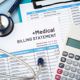 Expensive medical bills crowding a tabletop alongside a calculator and stethoscope