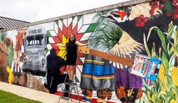Wendy DesChene installing a 50-foot mural depicting the history and culture of Poarch Creek Indians