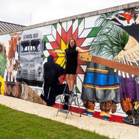 Wendy DesChene installing a 50-foot mural depicting the history and culture of Poarch Creek Indians