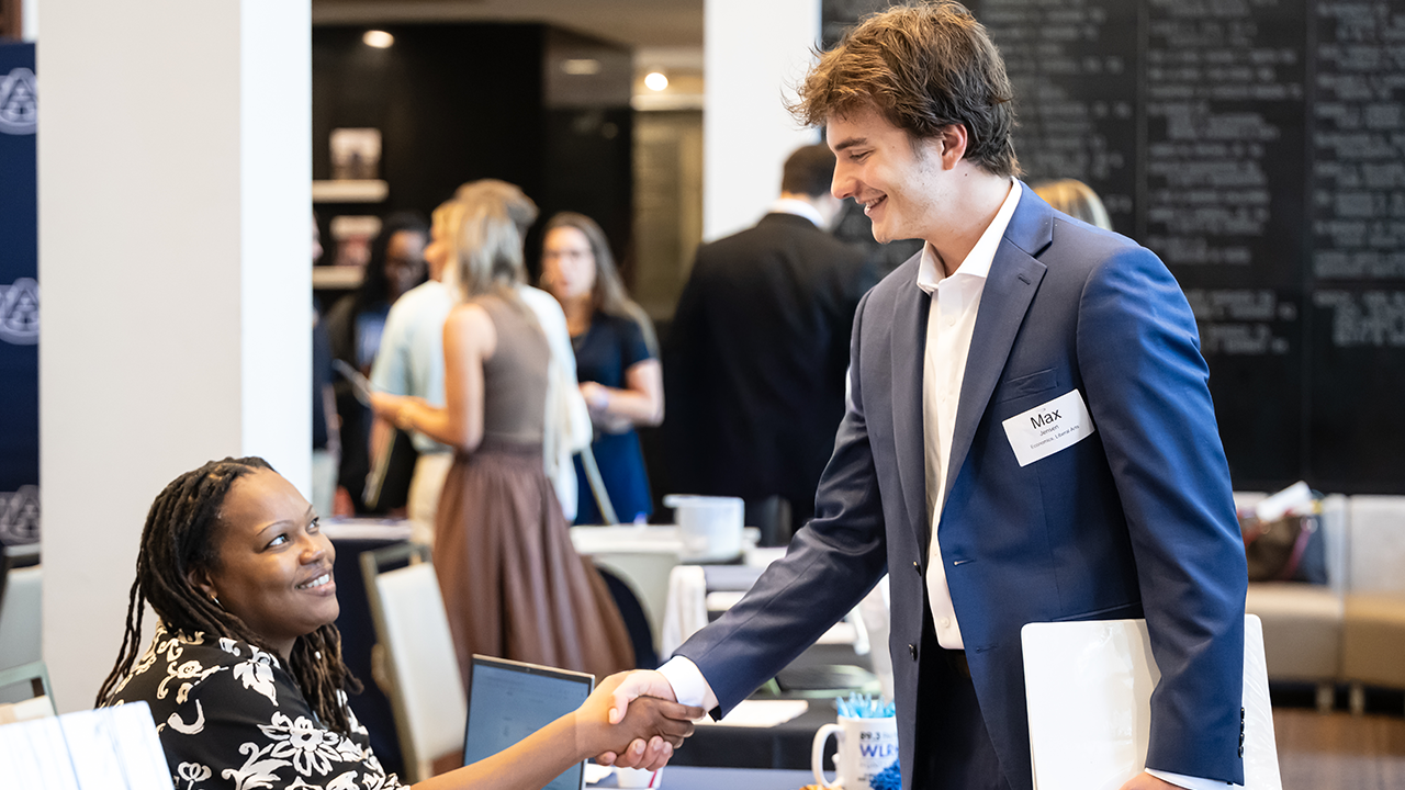 A student shakes hands with a potential employer at a career fair
