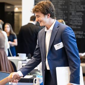 A student shakes hands with a potential employer at a career fair