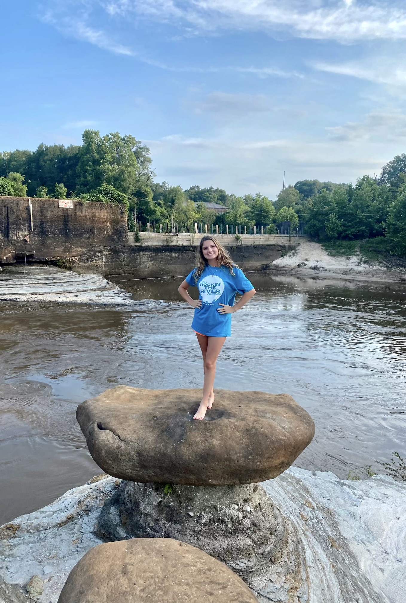Mikailie Caulder stands on a rock in front of the Elba Dam