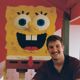 Caleb Eason sitting beside a statue of SpongeBob
