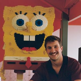 Caleb Eason sitting beside a statue of SpongeBob