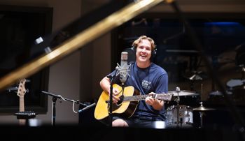 Student playing guitar and recording a song in the Lucky Man Studio