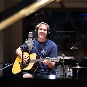 Student playing guitar and recording a song in the Lucky Man Studio