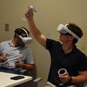 Two students using VR headsets and remotes to conduct virtual flight checks