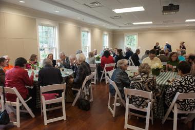 A room full of people sitting at round tables and eating lunch at the Center for Arts and Humanities