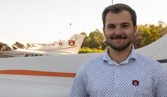 Noah Henry posing for photo in front of Auburn airplane fleet