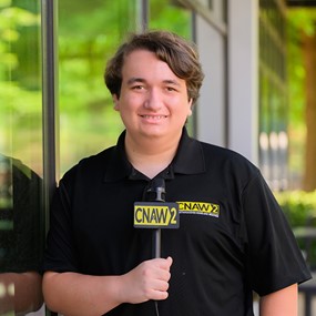 Colin Scroggins holding a CNAW2 News microphone