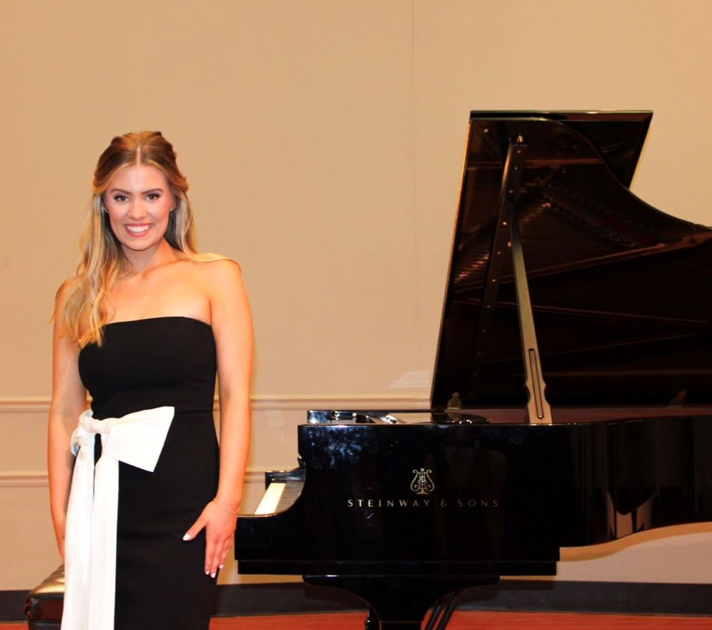 Julia Herrin posing for a photo beside a Steinway piano