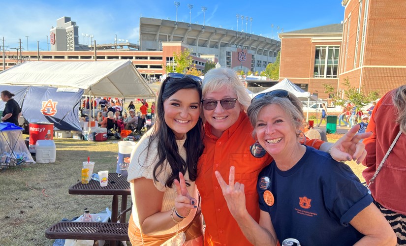 cheerful photo of three women posing together at an outdoor event,