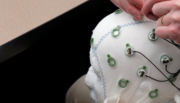 Richard Macatee fits brain sensors to a skull cap in the lab