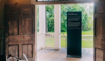 The Out of Whole Cloth exhibit sign standing in the doorway of a plantation house