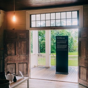 The Out of Whole Cloth exhibit sign standing in the doorway of a plantation house