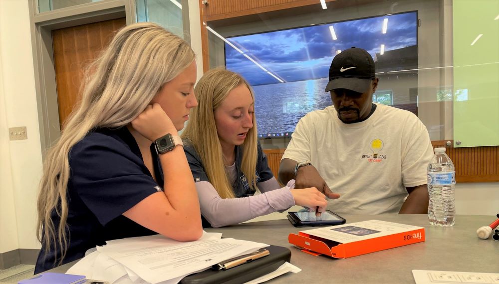 Auburn speech-language pathology students show a TBI Camp participant how to use assistive technology