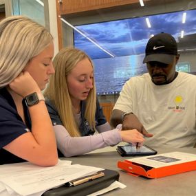 Auburn speech-language pathology students show a TBI Camp participant how to use assistive technology
