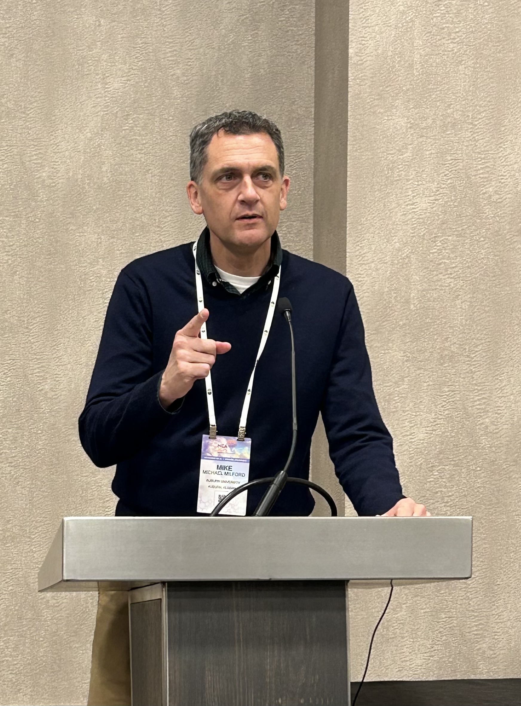 Mike Milford speaking at a podium.