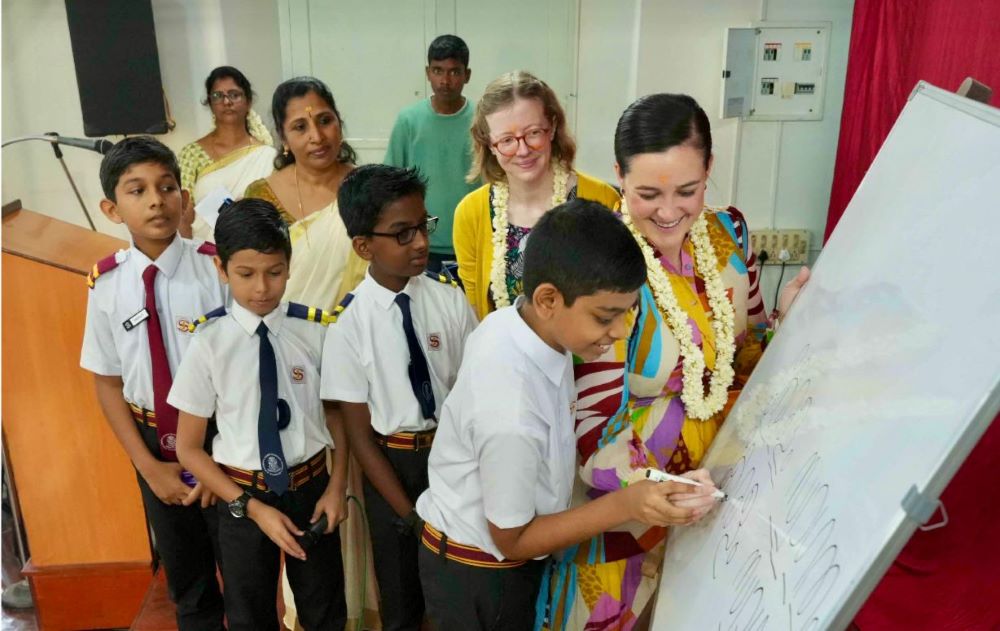 Laura West Ramkorun writing on a whiteboard with students