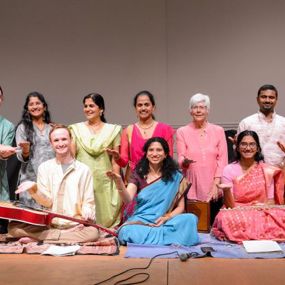 Group of people standing on a stage with indian music instruments