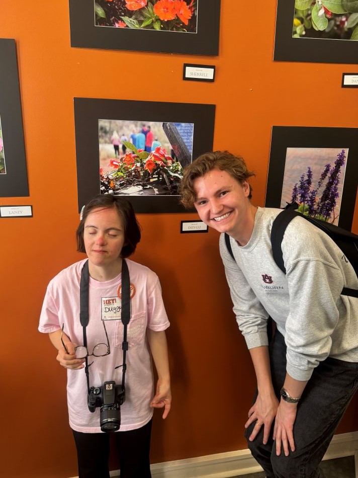 Braveheart artist and Aviation Leadership student posing for photo in front of flower photography