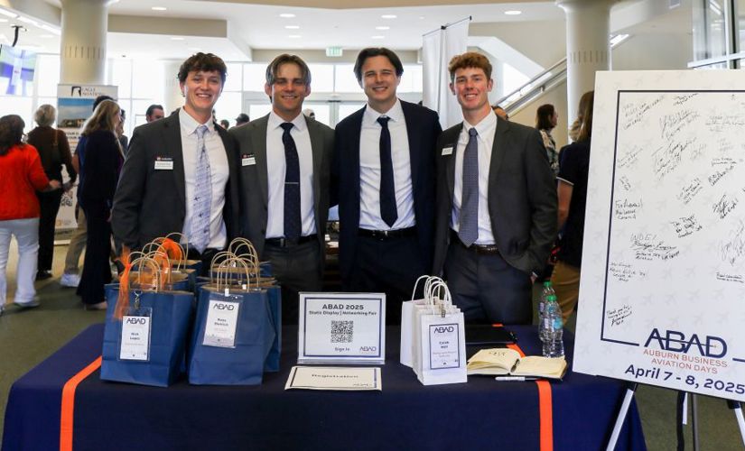four students standing behind a conference table posing for a photo