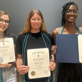 three female students standing together holding award certificates 