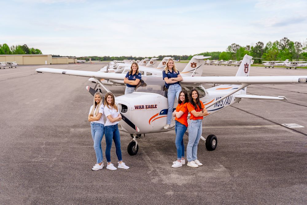 The War Eagle Women teams competing in ARC pose with an Auburn University plane