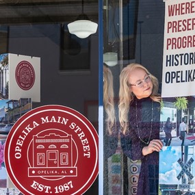 executive director of Opelika Main Street Kelsey Sullivan hanging a sign about historic preservation