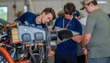 Auburn aviator pointing to parts of a plane engine