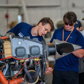 Auburn aviator pointing to parts of a plane engine
