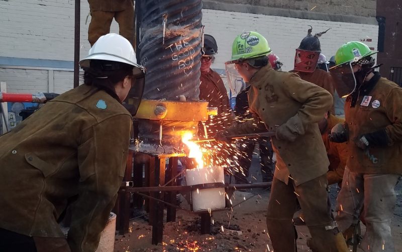 People pouring hot iron into a container