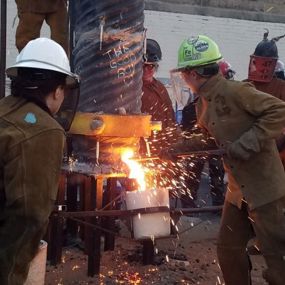 People pouring hot iron into a container