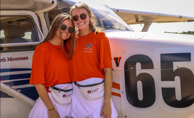 Elizabeth Moorman and Maggie Hearn stand in front of the Team 64 Skyhawk airplane