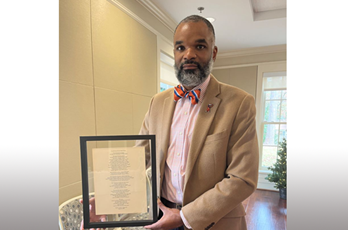 Ernest Gibson holds a framed copy of his poem "This Land," presented to him by the John R. Lewis Legacy Institute