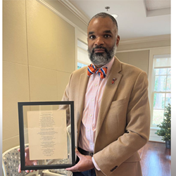 Ernest Gibson holds a framed copy of his poem "This Land," presented to him by the John R. Lewis Legacy Institute