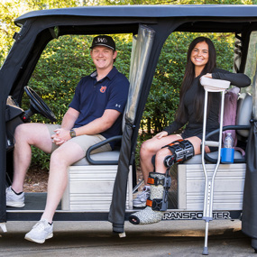 Kendal, on crutches, and Jack sitting in the jAUnt golf cart